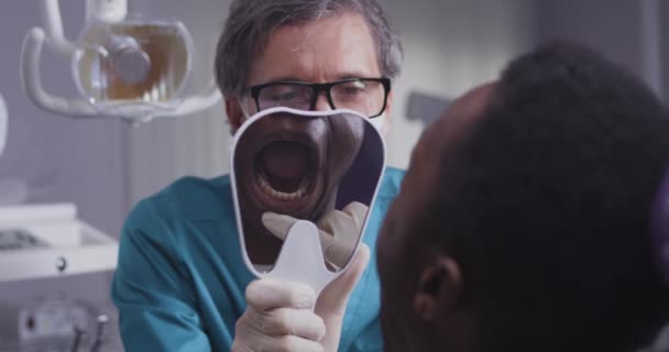 Dentista che consulta un uomo di colore in clinica — Video Stock