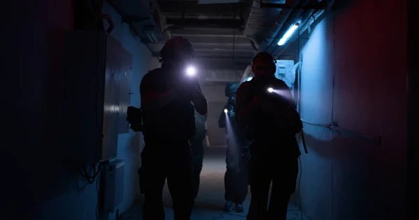 Soldiers with flashlights inspecting dark corridor