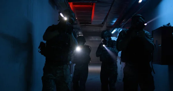 Soldiers with flashlights inspecting dark corridor — Stock Photo, Image