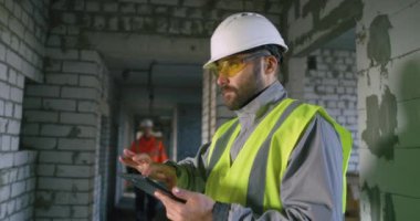 Erkek mühendis tarama tableti ve inşaat alanındaki danışman iş arkadaşı