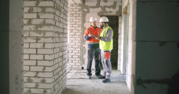 Contractors discussing construction data on tablet in corridor — Stock Video