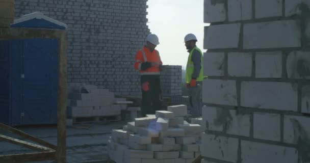 İnşaatçılar tuğla inşaatın bitmesini tartışıyor — Stok video