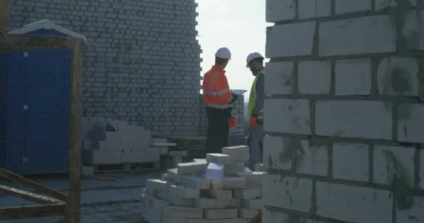 Constructeurs utilisant une tablette sur le dessus du bâtiment en brique — Video