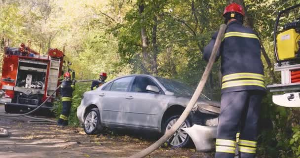 Firefighters extinguishing fire on broken car — Stock Video