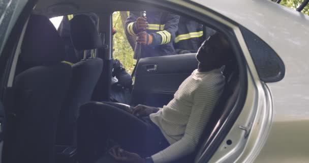 Rescuers abertura de carro com o homem étnico inconsciente — Vídeo de Stock