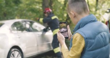 Çocuk, kazadan sonra kadınları kurtaran itfaiyecileri kaydediyor.