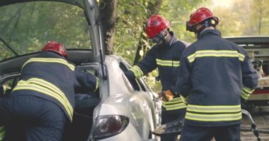 İtfaiyeciler arabanın camını kırıyor.