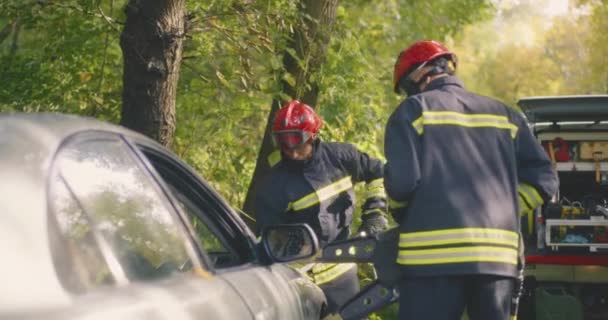 Bombeiros desmontando carro danificado após acidente — Vídeo de Stock