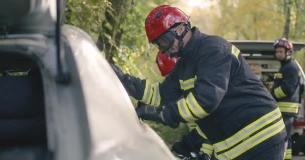 Bomberos tratando de abrir el coche — Vídeos de Stock