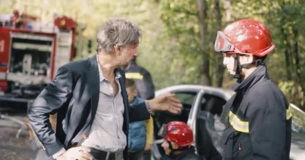 Idade Média vítima masculina conversando com resgatador perto de carro quebrado — Vídeo de Stock