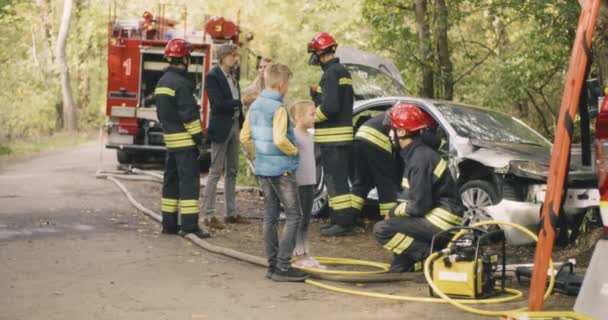 Familjen pratar med brandmän efter en trafikolycka — Stockvideo