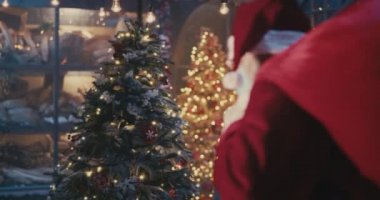Maskeli Noel Baba Noel ağacının yanından geçiyor.