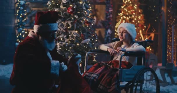 Święty Mikołaj mówi i daje prezent niepełnosprawnej dziewczynie — Wideo stockowe