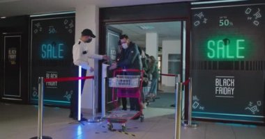 Gardiyan müşterilerden alışveriş merkezinin girişinde el dezenfekte etmelerini istiyor.