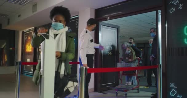 Diverse Menschen laufen mit Thermometer und desinfizierenden Händen in Einkaufszentrum an der Wache vorbei — Stockvideo