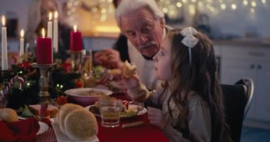 Küçük kız ve büyükbaba Noel yemeğinde konuşuyor.