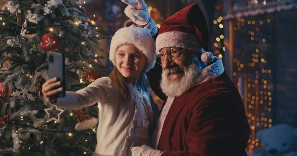 Lycklig flicka som tar selfie med jultomten — Stockfoto