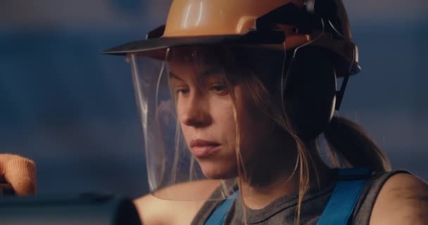 Trabajadora enfocada en casco protector trabajando en equipo pesado — Vídeo de stock