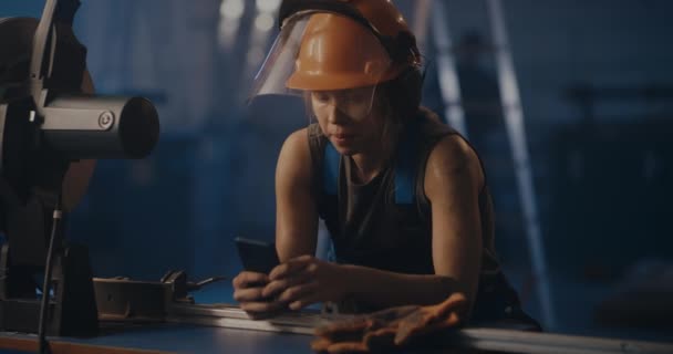 Vrouwelijke arbeider met behulp van telefoon in de fabriek workshop — Stockvideo