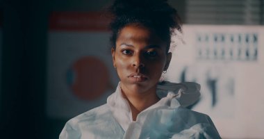 Etnik tıp doktoru koruyucu giysiyi çıkarıyor.