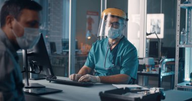 Öksüren adam hastanede doktorla konuşuyor.