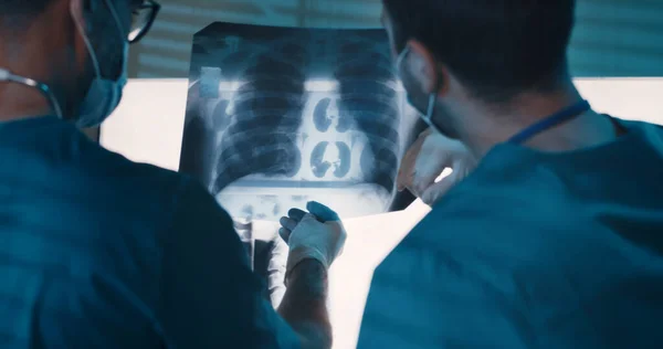 Médicos examinando raios X contra lâmpadas — Fotografia de Stock