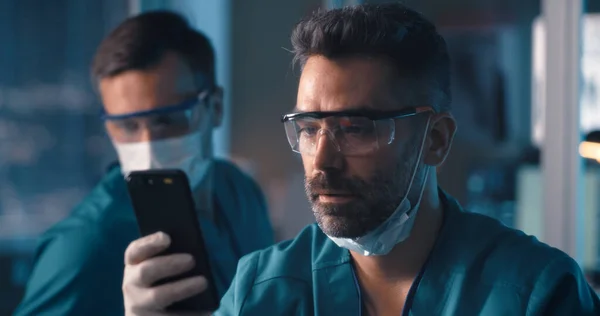 Médico usando smartphone durante a pausa no laboratório — Fotografia de Stock