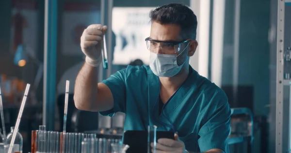 Médico masculino analisando amostras e usando tablet em laboratório — Fotografia de Stock