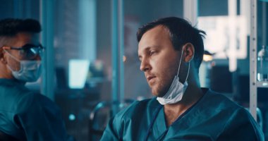 Yorgun doktor, laboratuarda meslektaşıyla konuşuyor.