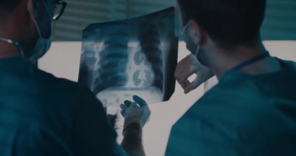 Male doctors examining X ray against lamps — Stock Video