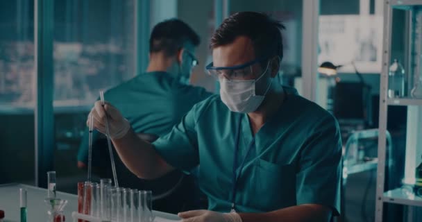 Мужчина врач делает заметки и исследует вакцину — стоковое видео