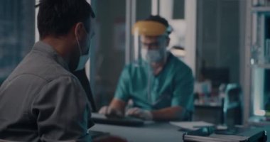 Öksüren adam hastanede doktorla konuşuyor.