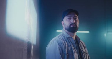 Parlak LED ekranın yanında sakallı teknisyen