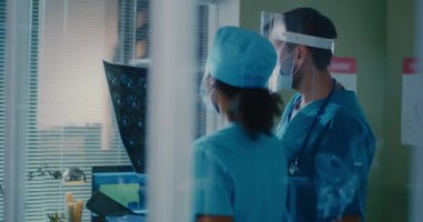 Erkek ve kadın doktorlar röntgen görüntülerini birlikte analiz ediyorlar.