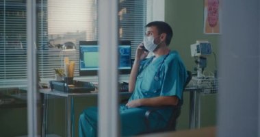 Tıbbi pratisyen, laboratuvarda akıllı telefondan konuşuyor.