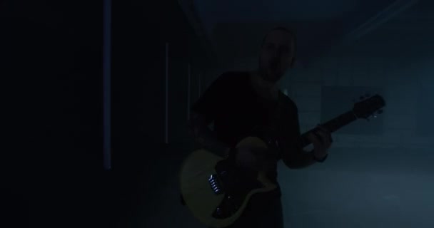 Rocker energic masculin cântând la chitară lângă lămpi — Videoclip de stoc