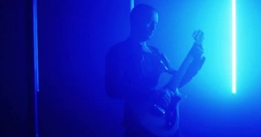 Parlak ışık altında elektro gitar çalan profesyonel bir müzisyen