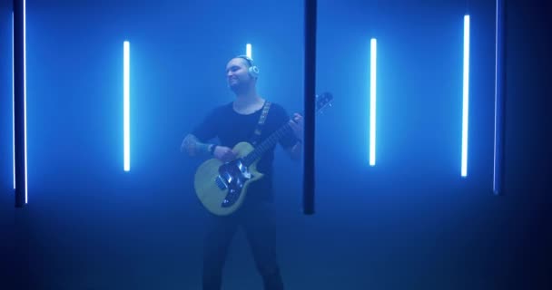 Man rocker spelar gitarr i cirkel av blå lampor — Stockvideo
