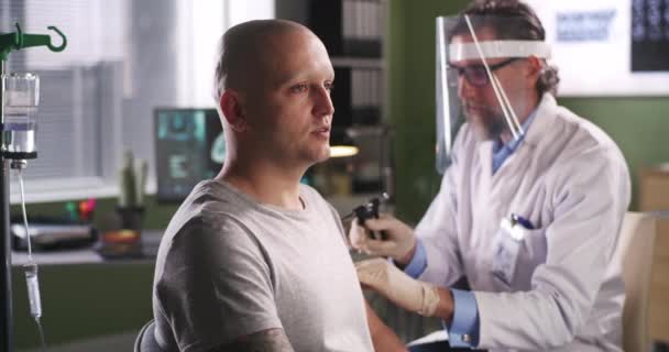 Bärtiger Arzt injiziert Impfstoff an glatzköpfige Patientin — Stockvideo