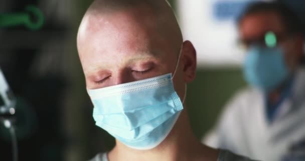 Upprörd onkologipatient i mask tittar ner — Stockvideo