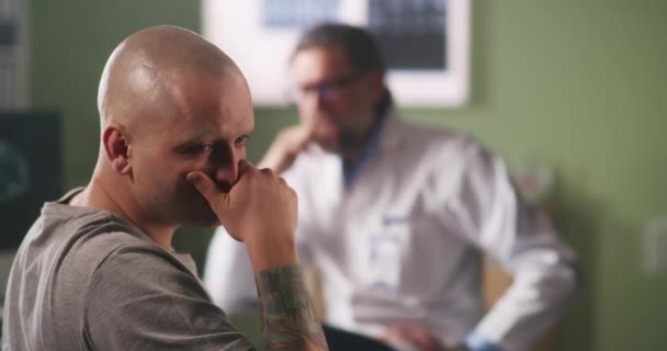 Plešatý muž reaguje na zprávy kapely a mluví s onkologem — Stock video