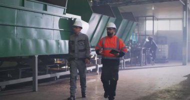 Atölyede teftiş sırasında yürüyen ve konuşan erkek mühendisler