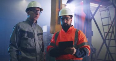 Erkek mühendisler fabrika tabletindeki verileri tartışıyor