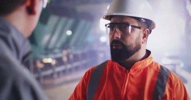 Sakallı müfettiş fabrikadaki işçiyle konuşuyor.