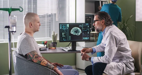 Ώριμος ογκολόγος εξηγεί CT εικόνα στον ασθενή κατά τη διάρκεια της χημειοθεραπείας — Φωτογραφία Αρχείου