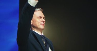 Olgun politikacı sahnede el sallıyor