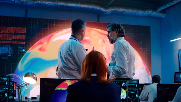 Erkek meslektaşlar ekoloji kontrol merkezinde hava sıcaklığını tartışıyor