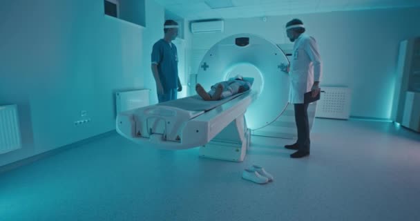 Многонациональные врачи и пациенты обсуждают результаты компьютерной томографии после процедуры — стоковое видео