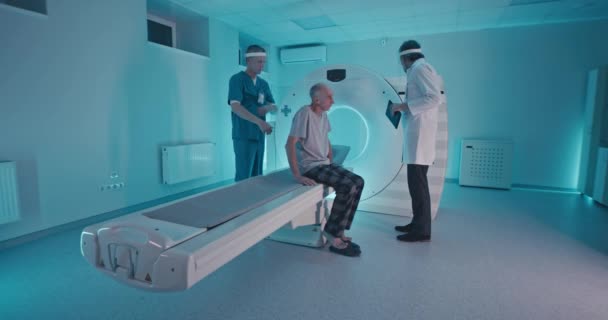 Male doctors preparing elderly man for CT scan — Stock Video