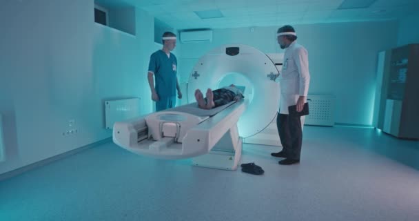 Врачи мужского пола заканчивают томографию пожилого мужчины — стоковое видео